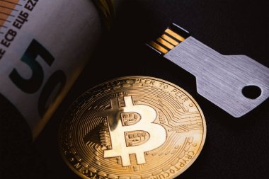 Bitcoin coin and usb flash drive in the form of a metal key on a black background. Soft focus.