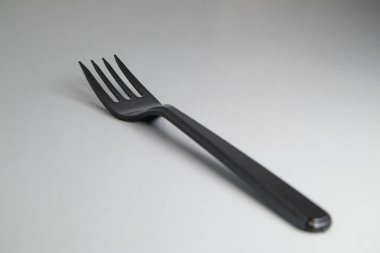 Black disposable plastic fork close-up. Disposable dishes. Soft focus.
