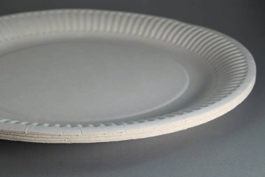 Close-up of disposable white paper plates on table. Soft focus.