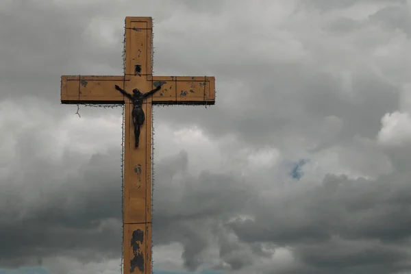 A large cross on a background of dark clouds. Cross with free space for text.