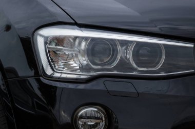 Headlight of a modern prestigious black car close-up.