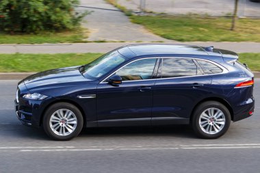 A dark blue SUV is driving on an asphalt street. Jaguar F-PACE, Riga, Latvia - 15 Aug 2022.