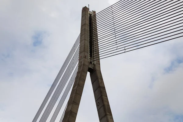 Cable-stayed bridge concrete support and cables on sky background.