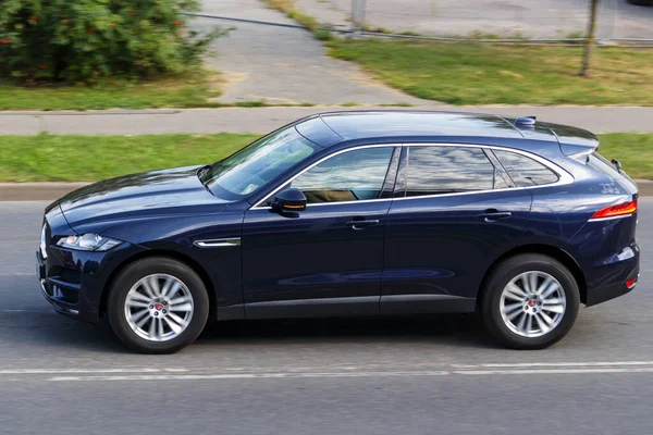 A dark blue SUV is driving on an asphalt street. Jaguar F-PACE, Riga, Latvia - 15 Aug 2022.