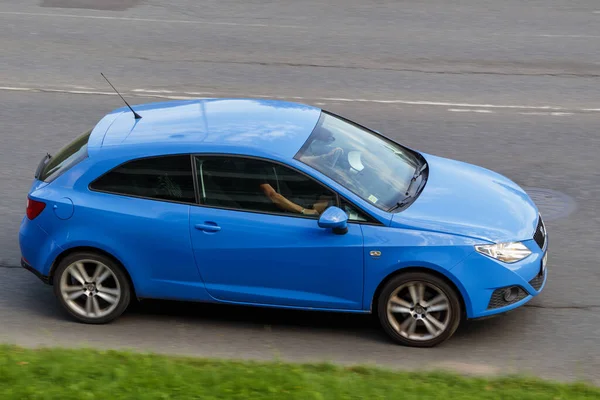 A small, compact car is driving on an asphalt street. Light blue Seat Ibiza. Riga, Latvia - 15 Aug 2022.