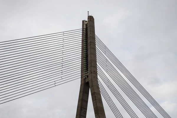 A close-up of the cable-stayed bridge\'s concrete support and metal cables.
