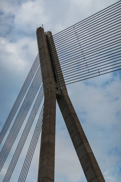 Cable-stayed bridge mast and cables on sky background.