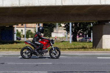 Red motorcycle is driving on street. Ducati Monster 695. Riga, Latvia - 04 Sep 2022.