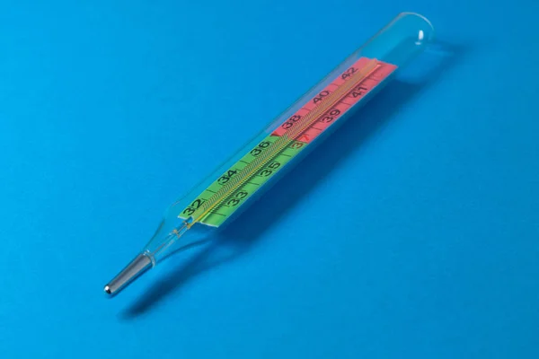 Medical mercury thermometer on a blue background. Thermometer for measuring body temperature.