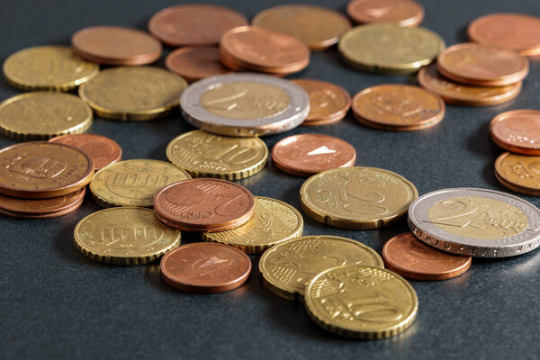 Scattered euro coins on black table close-up. Soft focus.
