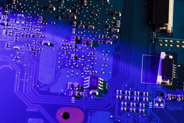 Circuit board close-up. Electronic circuit board is illuminated in blue light. Soft focus.