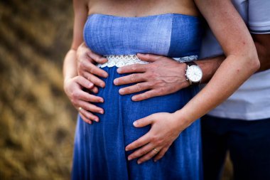 Kocası elleri olan hamile gelin ve beyaz.