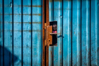 Asma kilitli paslı metal bir kapı.