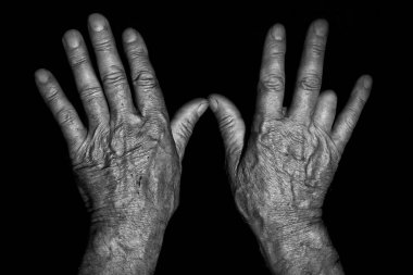 Yaşlı eller siyah beyaz bir eli arka planda tutuyorlar.