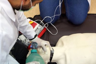 Temel yaşam desteği sırasında bir öğrencinin otomatik dış defibrilatörle simülasyon mankeni üzerinde nefes torbası (Ambu) kullanması. Benzetim eğitim senaryosu