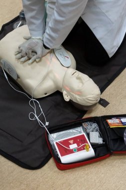 Temel yaşam desteği sırasında otomatik dış defibrilatörlü bir simülasyon mankeni üzerinde göğüs kompresyonu. Simülasyon eğitim senaryosu. Dikey