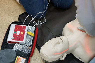 Temel yaşam desteği sırasında bir öğrencinin simülasyon mankeni üzerinde otomatik dış defibrilatörle göğüs kompresyonu. Benzetim eğitim senaryosu