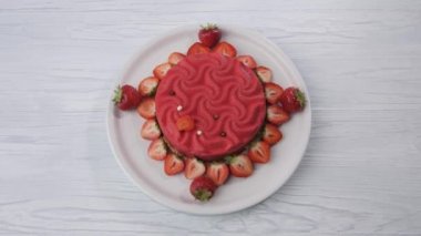 Pink strawberry cake spins on a white plate.