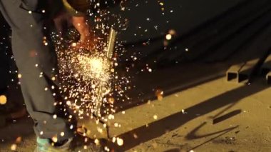 İşçilerin elleri çalışan bir açı öğütücüsünü tutar.