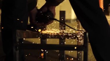 İşçilerin elleri çalışan bir açı öğütücüsünü tutar.