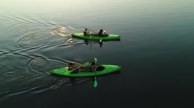 Volyn, Ukrayna - 08 Ağustos 2021: Temiz suda yüzen genç Ukraynalı kadın ve erkeklerle iki yeşil kano.