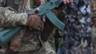Kyiv, Ukrayna - 31 Mart 2022: Askerlerin elleri bir Kalaşnikof tüfeğini tutuyor, fırlatıyor ve dans ederken sallanıyor.