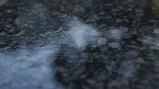 Gotas de chuva em câmera lenta caem em uma superfície de granito. — Vídeo de Stock