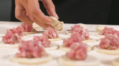 Kadın aşçı parmakları boşluğu doldurur. Hamur köftesi yapmak için kıymalı yuvarlak hamur..