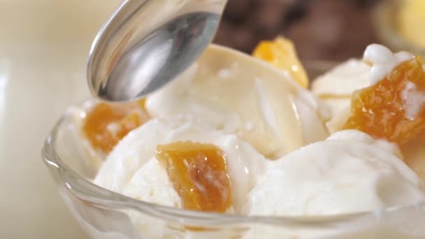 Ein Teelöffel wird in weißes Eis mit Mango-Scheiben getaucht. — Stockvideo