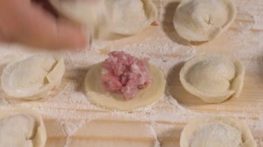 Kadın aşçı parmakları boşluğu doldurur. Hamur köftesi yapmak için kıymalı yuvarlak hamur..