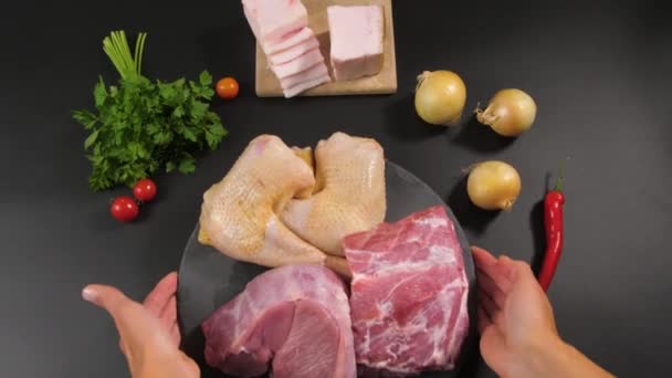 Female hands put on a background of a stone plate with pieces of raw meat of veal, pork, chicken. — Stockvideo