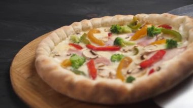 Çelik kürekli pizza kahverengi ahşap tepsiye konur..
