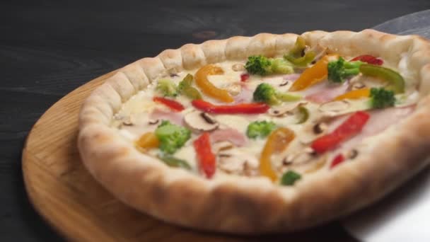 Pizza z łopatą stalową jest umieszczona na brązowej drewnianej tacy. — Wideo stockowe