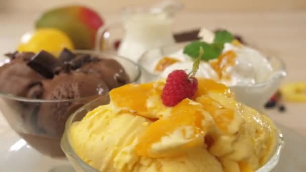 Taças de vidro cheias de sorvete com sorvete, chocolate, manga e banana. — Vídeo de Stock