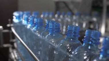 Boş mavi plastik şişeler taşıyıcı bantta taşınır. Maden suyu üretim tesisi.