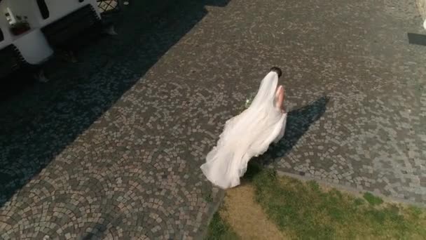 Bruden Vit Bröllopsklänning Med Bukett Händerna Går Gamla Kullerstenarna Flygbild — Stockvideo