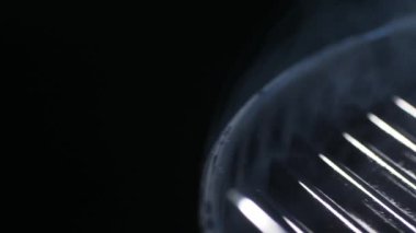 Siyah arka planda domuz sosisi ve sebzeli ızgara ızgara görünüyor. Duman var. Kızartma işlemi.