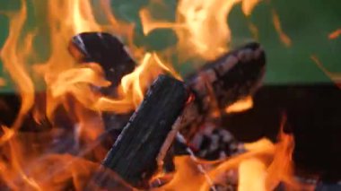 Yakacak odun brazier 'da yanıyor. Yarım çerçeve yeşil çimenlerin bulanık arka planıyla dolu. Diğer yarısı demir bir duvar..