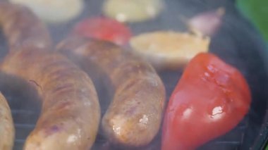 Bir adam ızgara sosisi yağla fırçalıyor. Sebzeli kızarmış sosis. Piknik konsepti.