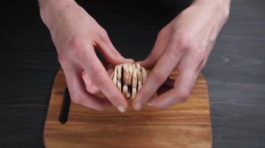 Male hands throw chopped pieces of champignon mushrooms on a wooden cutting board. Dark background. Ingredients.
