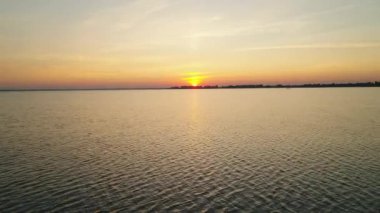 Sunrise on the lake. Aerial view of five kayaks with paddlers sailing towards the sun in the morning. Water tourism.