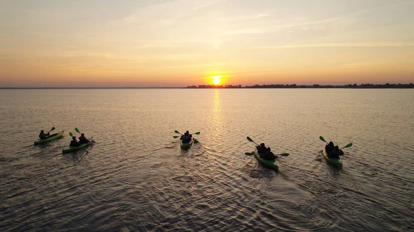 Aerial view of five kayaks with tourists. They sail to meet the sunrise. Extreme water trips.