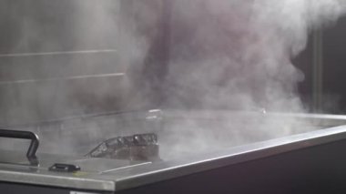 Industrial ultrasonic cleaning machine. Cleaning metal parts of the car engine in an ultrasonic bath. Lifting the cylinder head with valves and oil pan.