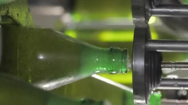 Dikey video. Endüstriyel santraldeki otomatik taşıyıcıda karbonatlı biraların üretimi ve şişelenmesi cam şişelere dönüştürülür. Yiyecek endüstrisi konsepti. Şişelenmiş içeceklerin üretimi.