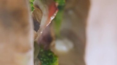 Dikey video. Fırında pizza pişirme süreci. Yakın plan. Peynir kaynıyor, biber, mantar, brokoli, jambon, hamur pişiyor. Yüksek sıcaklık.