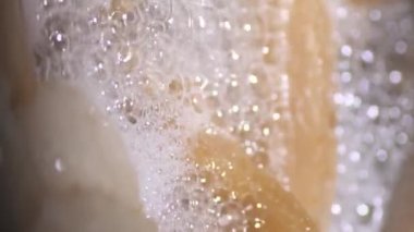 Dikey video. Altın hamurlu domuz yağı, bol köpüklü paslanmaz çelik bir tavada erir. Kamera hareketlerini kapat.