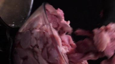 Dikey video. Siyah eldivenli bir aşçı cam kaseden paslanmaz çelik bir tavaya çiğ domuz eti taşır. kenardan durağan genel çerçeve.