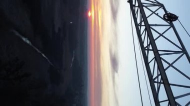 Dikey video. Tek bir vincin arka planında gün doğumu. Bir vincin altında uçmak.