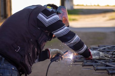 Kaynakçı, kaynakçı kaskıyla ızgarayı kaynaklıyor.