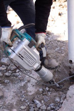 Adam beton kırıcıyla betonu kırıyor.